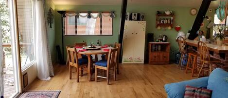 Un comedor acogedor con una mesa y sillas de madera, un refrigerador y una encimera de cocina con diversos objetos.