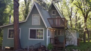 A small, single-story house with a steeply pitched roof, a front porch, and a small deck. - Head up to our creek cabin! (Payson)