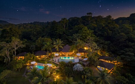 A resort with multiple buildings, a swimming pool, and lush greenery.
