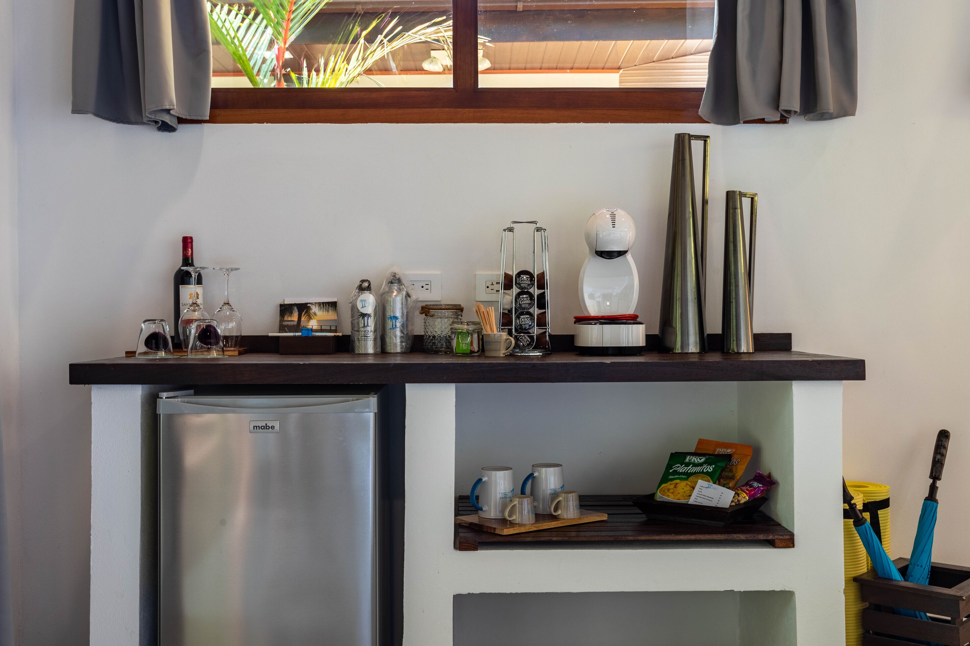 A kitchen with a refrigerator, coffee maker, and various kitchen items on the counter.