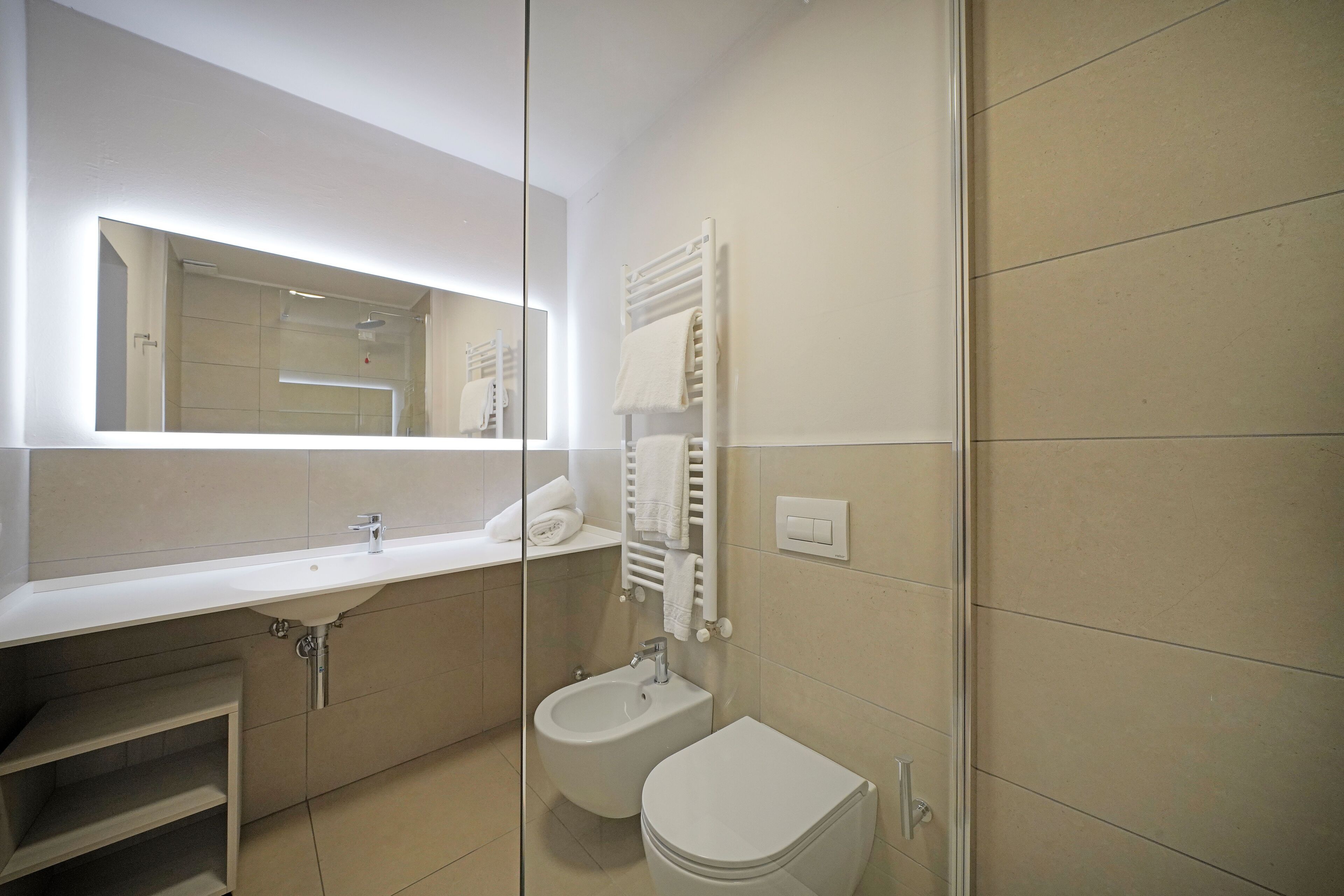 Ein modernes Badezimmer mit Waschbecken, Bidet und Toilette in Weiß.