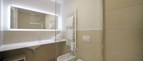 A modern bathroom with a white sink, bidet, and toilet.