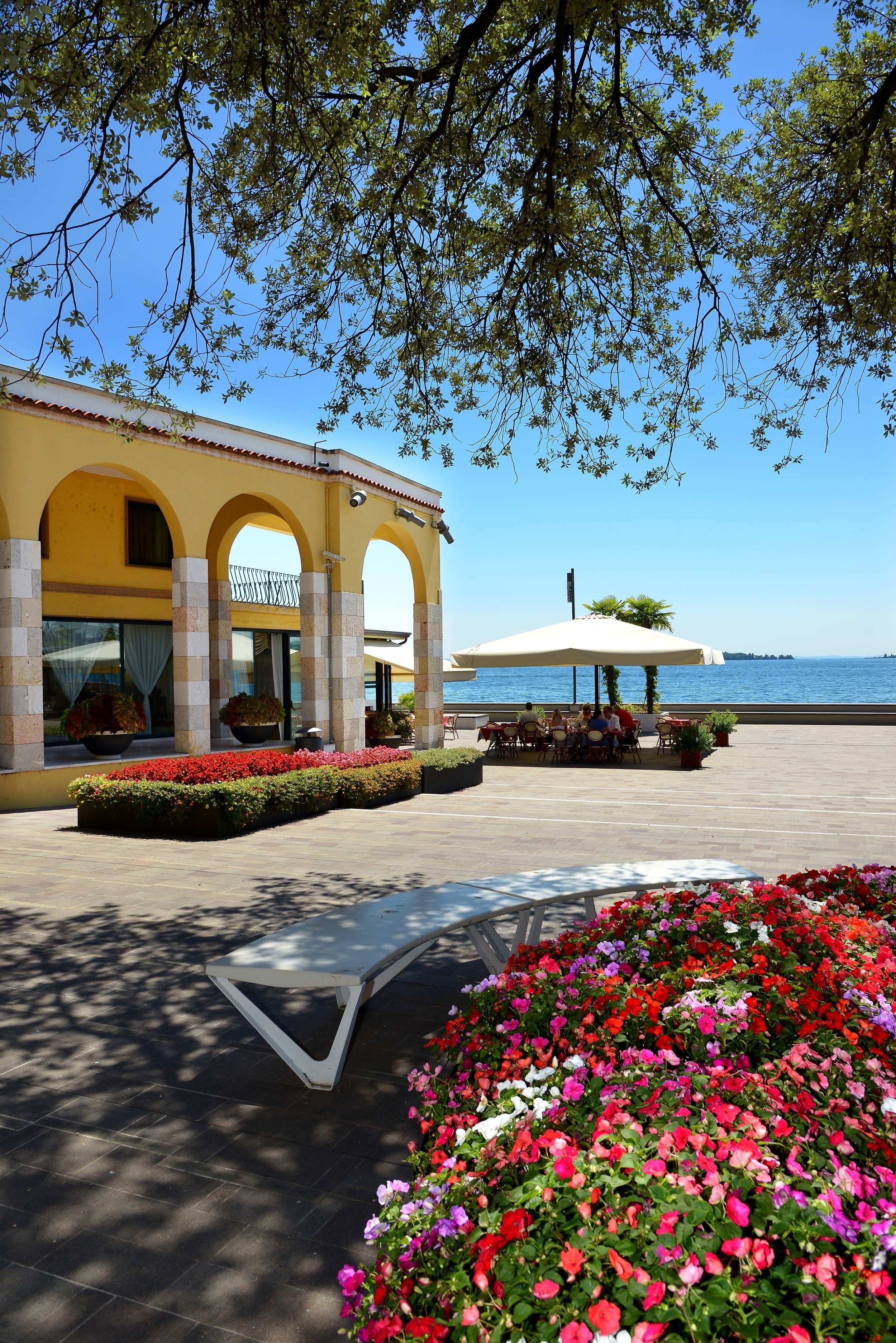 A building with arched windows and a patio area with tables and chairs.