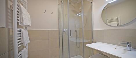 A modern bathroom with a glass-enclosed shower, a white sink, and a large mirror.