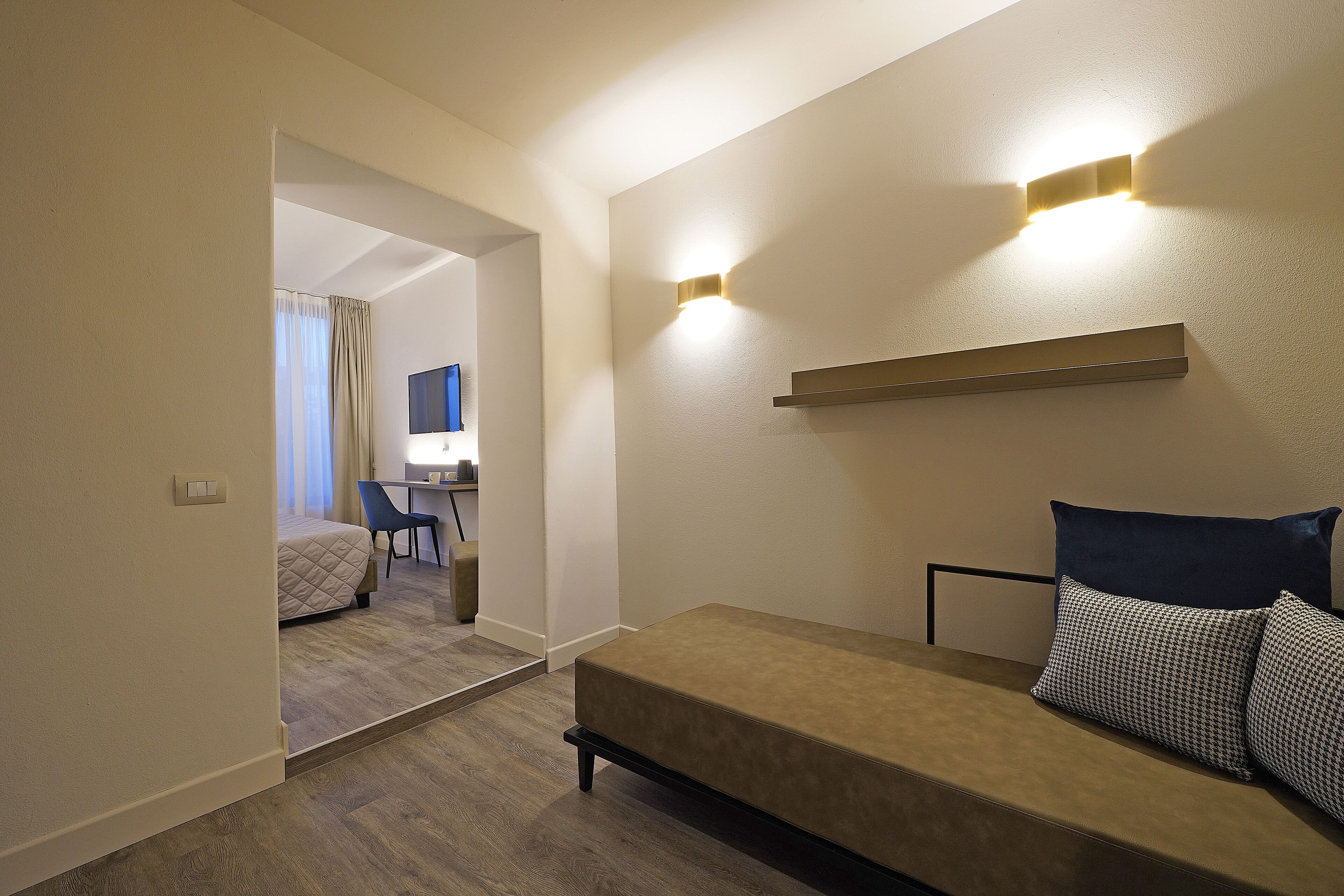 Une chambre d’hôtel moderne équipée d’un canapé-lit, d’un bureau avec une chaise et d’un miroir.
