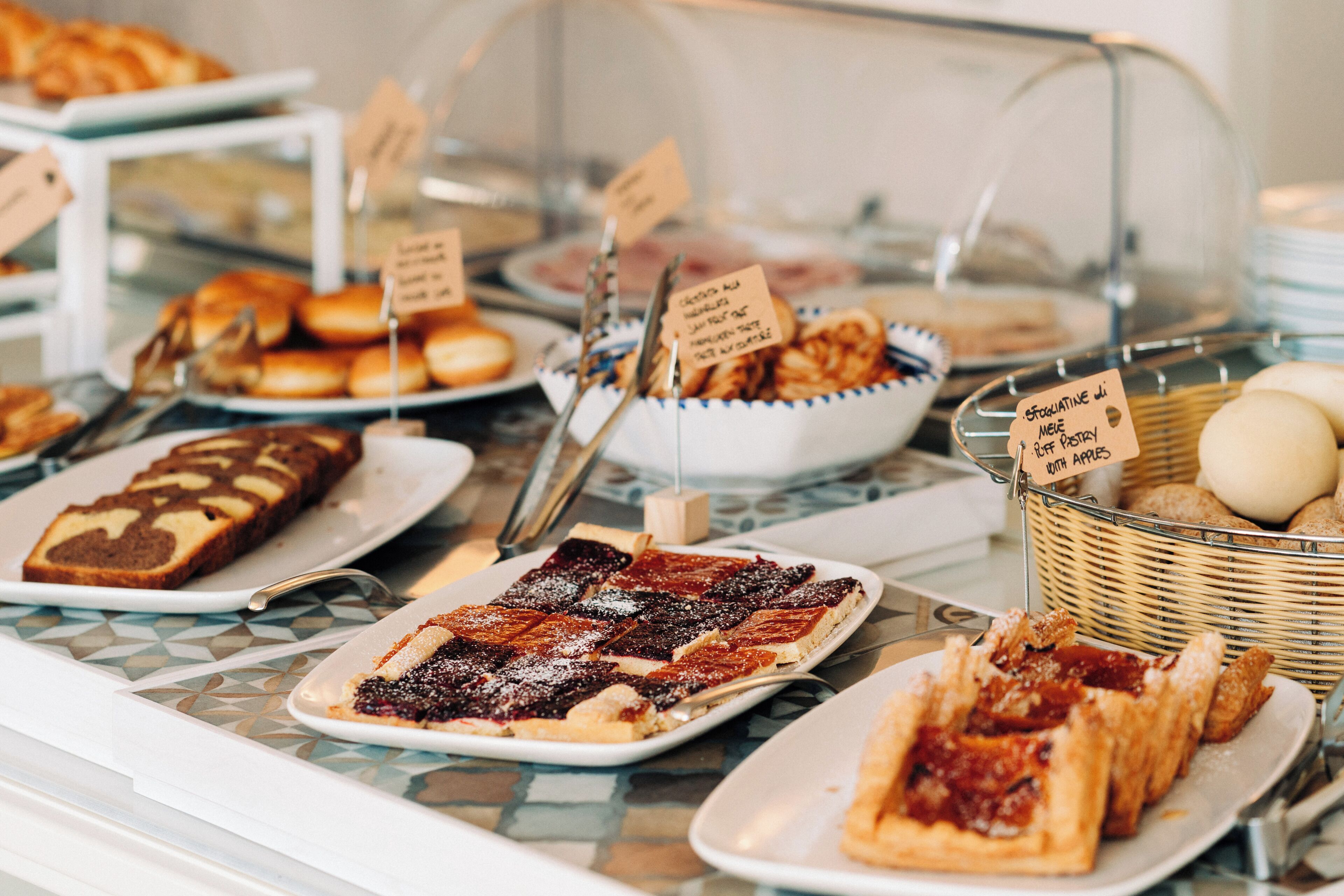 A buffet with various baked goods and pastries, including bread, pies, and cakes.