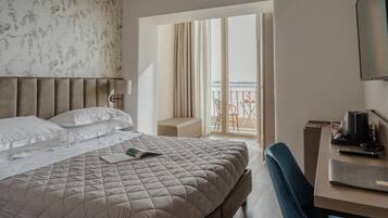 Habitación de hotel con una cama grande, un escritorio con una computadora portátil y un balcón con vistas.