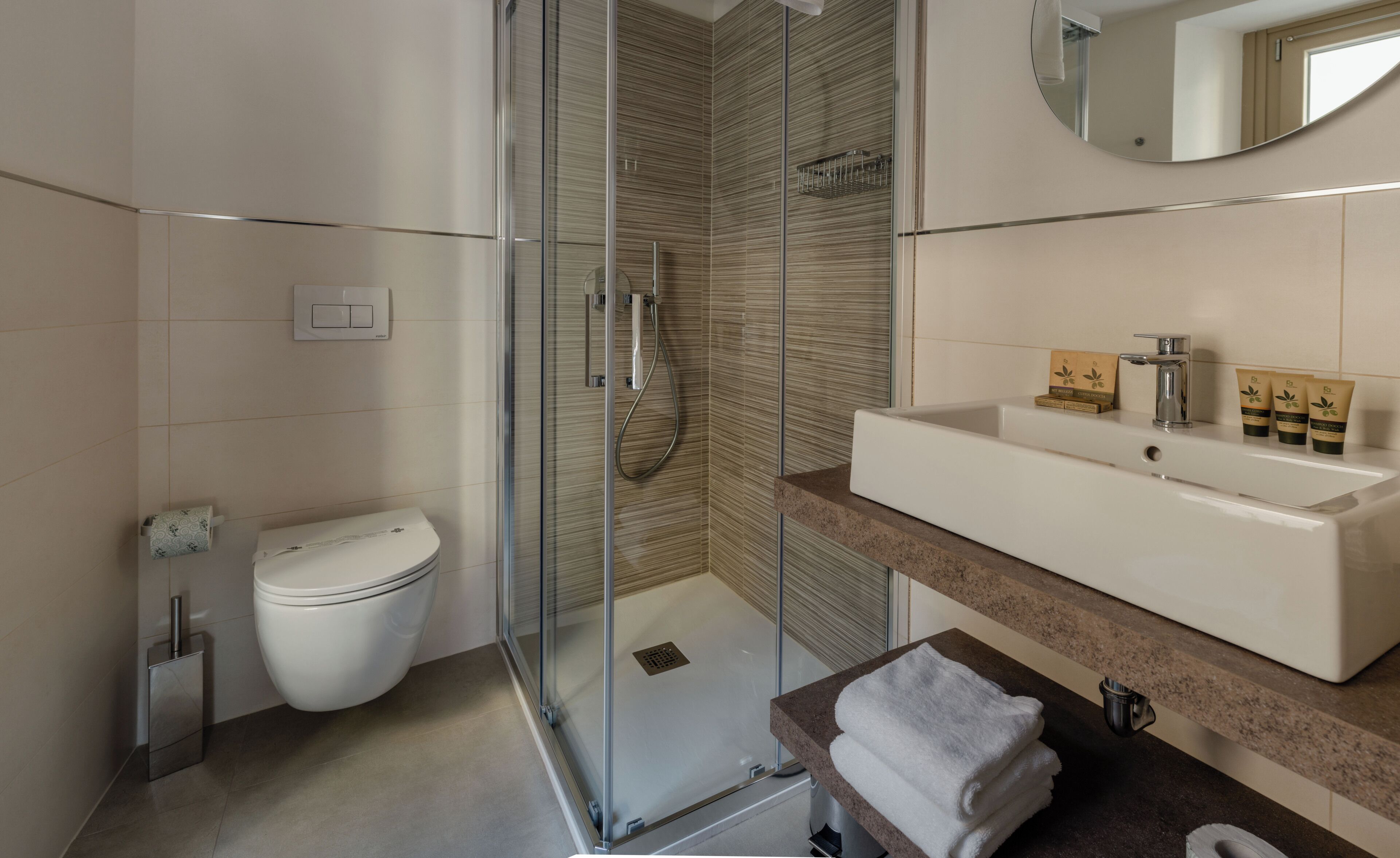 A modern bathroom with a glass-enclosed shower, a white toilet, and a vanity with a sink and mirror.