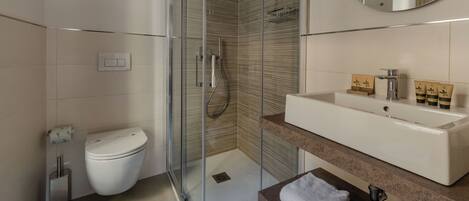 A modern bathroom with a glass-enclosed shower, a white toilet, and a vanity with a sink and mirror.