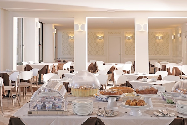 A banquet hall with tables set for a meal, white chairs, and a buffet area with food items. - Hotel Du Lac Gardone Riviera (Gardone Riviera)