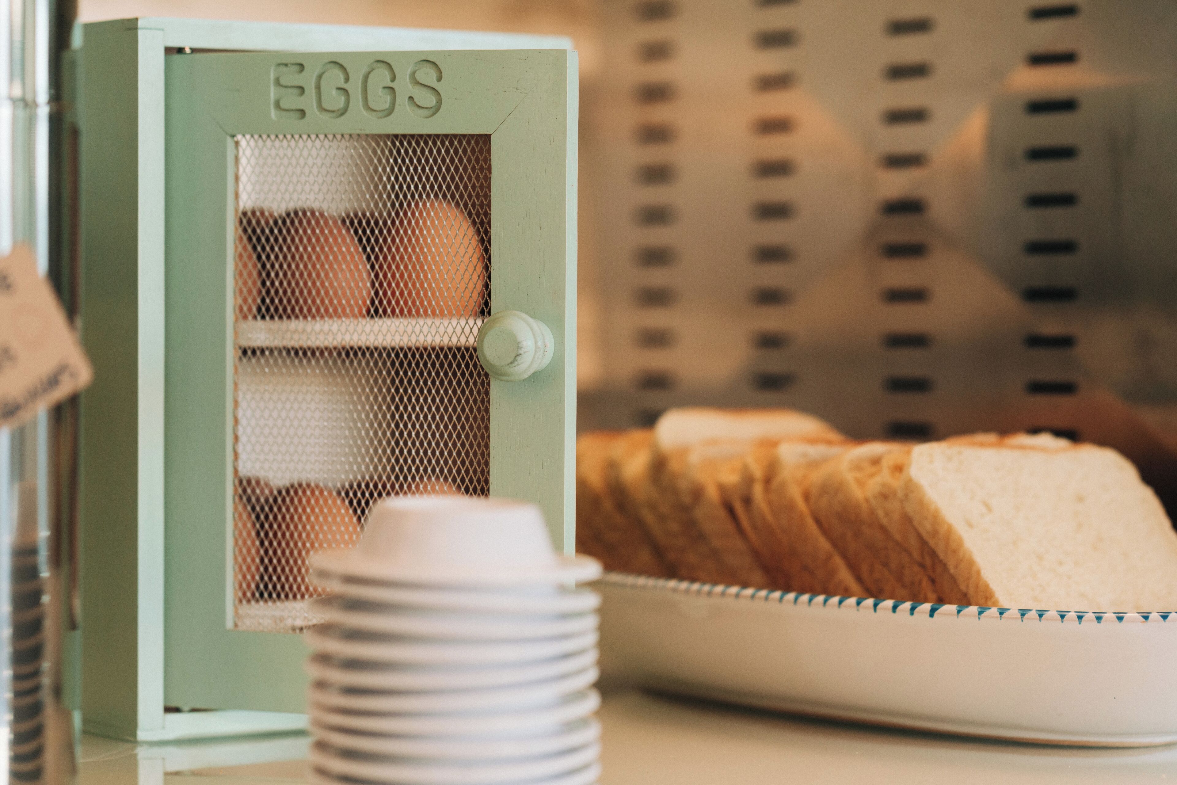 Una exhibición de pan con un recipiente verde etiquetado 'EGGS' en una panadería.