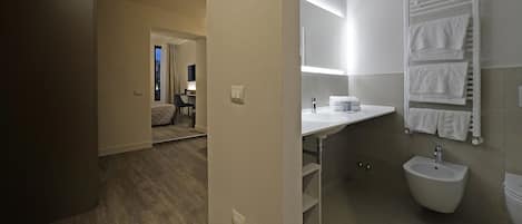 Un baño de hotel con lavamanos, bidé y perchero para toallas.