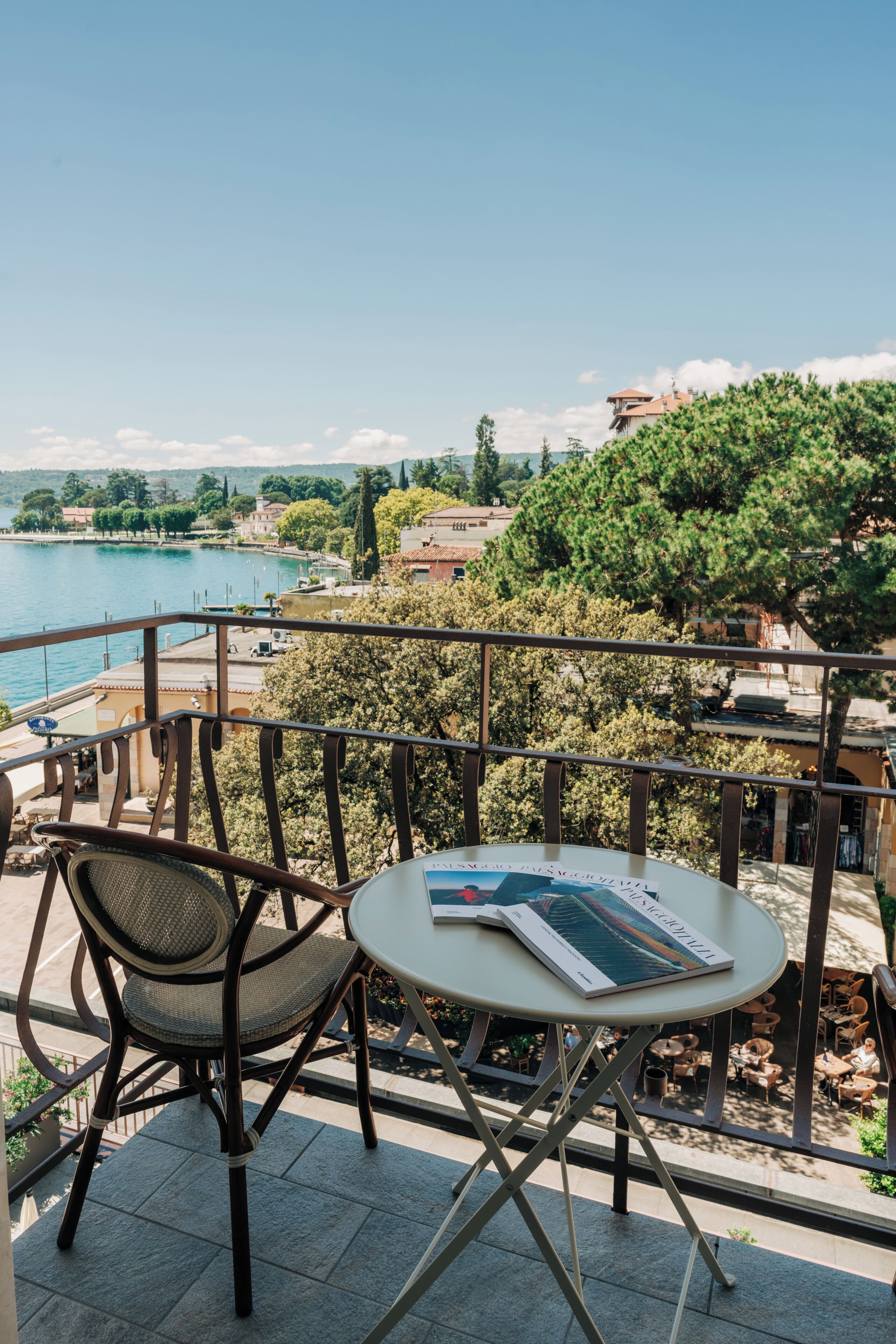 A balcony with a table and chairs overlooking a body of water and a town.