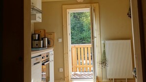 A kitchen with wooden cabinets, a stove, and a window leading to a deck.