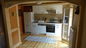 A compact kitchen with white cabinets, a dishwasher, an oven, and a window providing natural light.