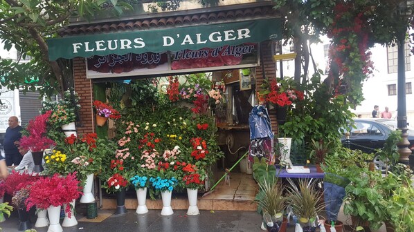 A flower shop named 'Fleurs d'Alger' with a variety of colorful flowers displayed outside.