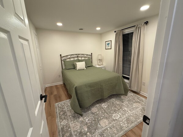 A bedroom with a bed, a nightstand, a lamp, a window with curtains, and a door. - Beautiful, quaint newly-renovated Keowee Key condo with golf course view! (Salem)
