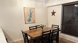 A dining room with a wooden table, black chairs, a map on the wall, and a star decoration.