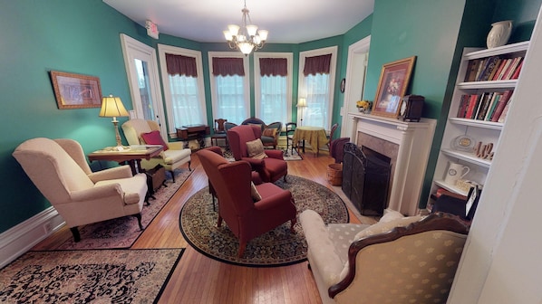 Una sala de estar con chimenea, una estantería y un comedor con sillas y una mesa.