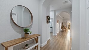 A hallway with a wooden console table, a round mirror, and a potted plant.