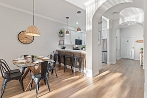 Uma cozinha moderna com armários brancos, ilha central e iluminação pendente.