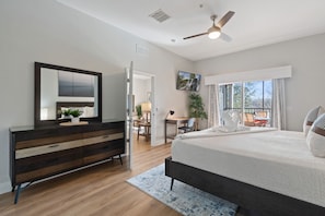 Quarto com cama grande, penteadeira, escrivaninha e vista para o exterior.