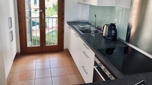 A modern kitchen with a stainless steel range hood, a coffee maker, and a glass on the counter. - Licensed Beautiful large 2 Bed Apartment in Puerto Pollenca. 2 pools and balcony (Puerto de Pollenca)