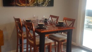 A dining table set with chairs, plates, bowls, and wine glasses.