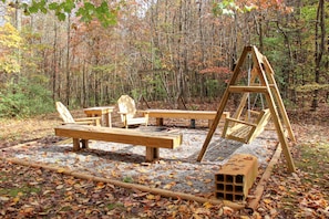Ein Schaukelstuhl und ein Picknicktisch in einem bewaldeten Gebiet mit herabgefallenen Blättern.
