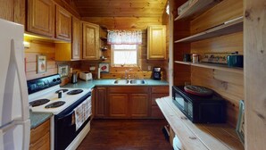 Una cocina funcional con muebles de madera, estufa, fregadero y microondas.