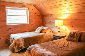 Ein gemütliches Cabin-Zimmer mit zwei Betten, einem Fenster und einem Nachttisch mit Lampe.