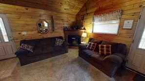 Un acogedor interior de cabaña con dos sofás, una chimenea y un espejo en la pared.