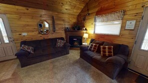 Un acogedor interior de cabaña con dos sofás, una chimenea y un espejo en la pared.