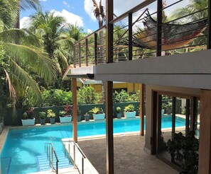 Un espace piscine offrant une vue dégagée sur la piscine, un hamac et la végétation environnante.