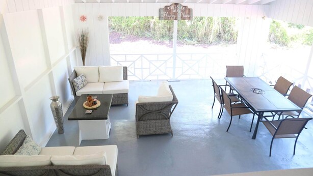 Un patio cubierto con una mesa de comedor y sillas, un sofá y una mesita de centro.
