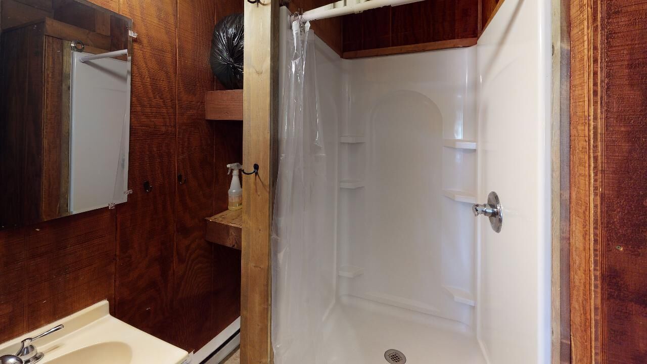 Un bagno con un mobile vanitario in legno, un lavandino bianco, uno specchio e un box doccia.