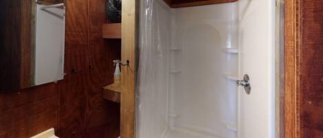 Un bagno con un mobile vanitario in legno, un lavandino bianco, uno specchio e un box doccia.
