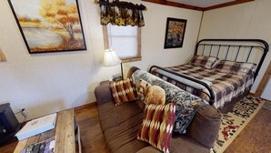 Un dormitorio con una cama, un sofá, una lámpara y un cuadro en la pared.