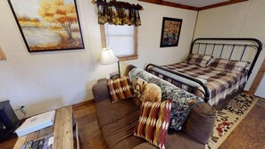 A cozy room with a bed, a sofa, and a small table.
