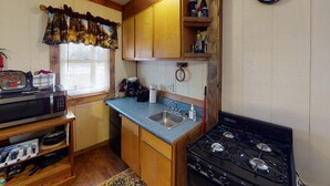 Una cocina compacta con microondas, estufa, pileta y alacenas de madera.