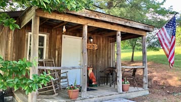 A rustic wooden cabin with a porch, a sign reading 'FOX DENZ', and an American flag.
