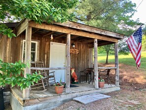 A rustic wooden cabin with a porch, a sign reading "FOX DENZ", and an American flag.