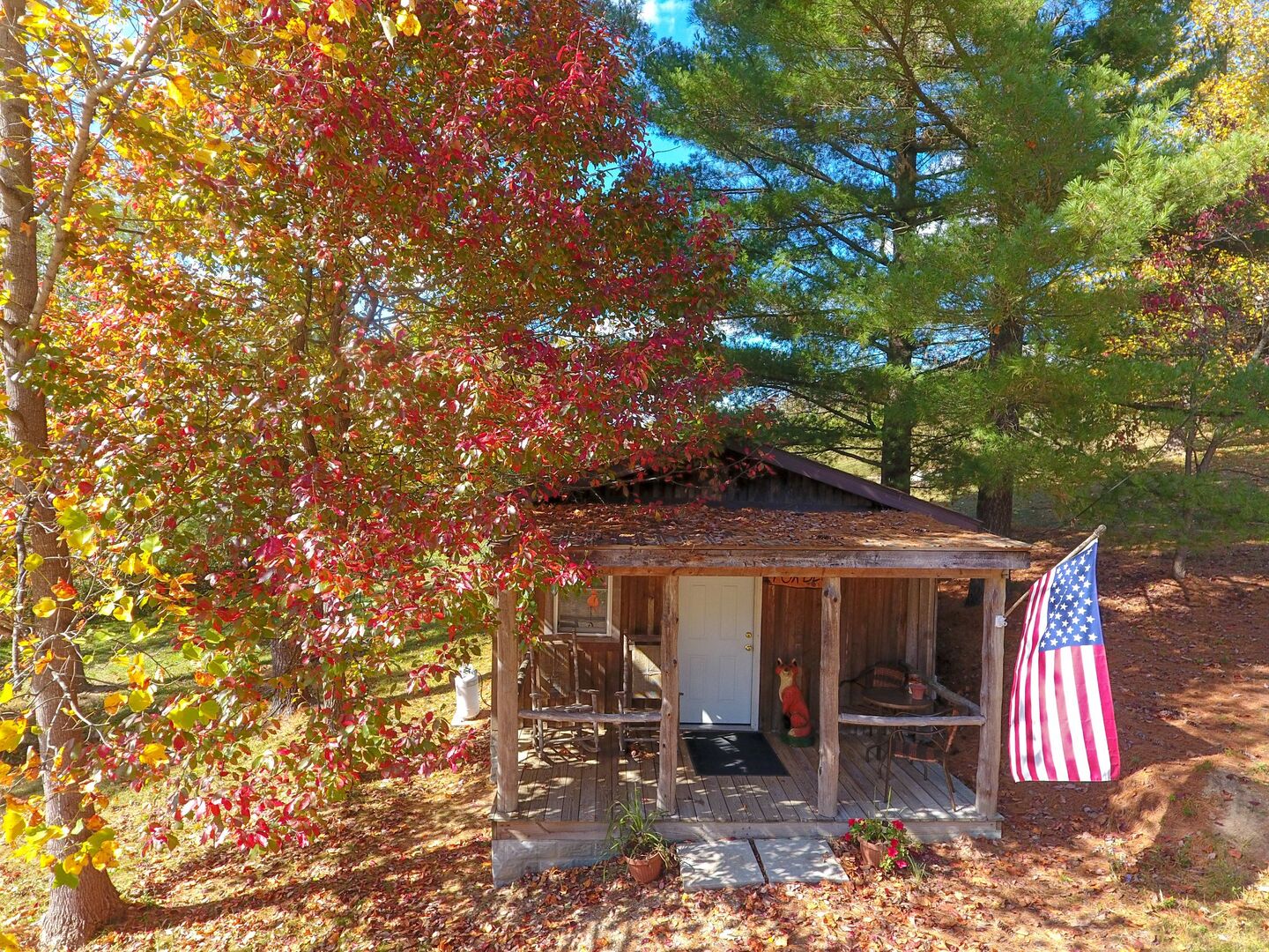 A rustic cabin with a porch, an American flag, and a squirrel statue.