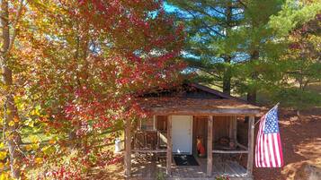 A rustic cabin with a porch, an American flag, and a squirrel statue.