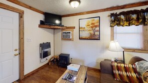 A cozy living room with a television, fireplace, and a painting on the wall.
