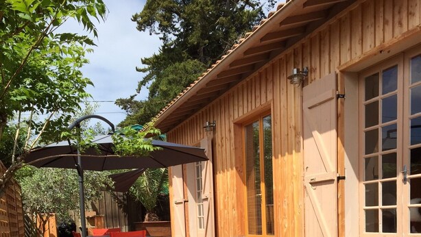 A wooden deck with a lounge area, outdoor furniture, and a wooden building with large windows. - Wooden house in the center of Cap Ferrets ans a quiet street 100 m from the market. (Lège-Cap-Ferret)