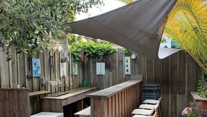 A wooden deck with a bar area, outdoor seating, and a shaded canopy. - Wooden house in the center of Cap Ferrets ans a quiet street 100 m from the market. (Lège-Cap-Ferret)
