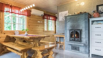A wooden interior with a stone fireplace, wooden benches, and a table with a vase.