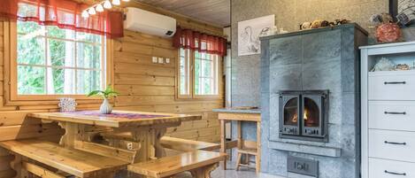 Un interior de madera con chimenea de piedra, bancos de madera y una mesa con un florero.