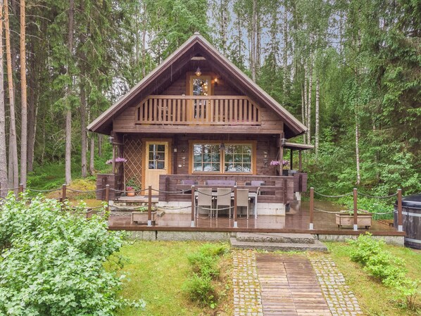 A wooden cabin with a balcony, a covered porch, and a stone pathway leading to the entrance. - Joutsen by Interhome (Ruovesi)